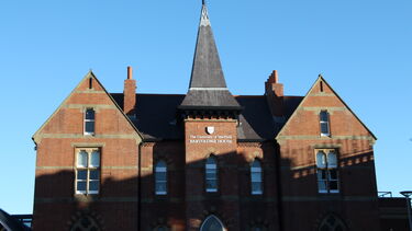 Centre building of Bartolome House half with the top half within the sun and the bottom half in shadow.