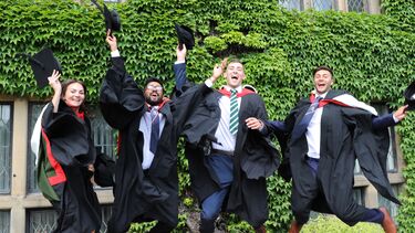 Graduates jumping with hats in hands