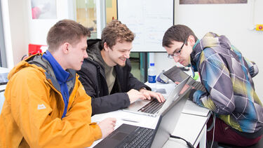 A group of people sat together working on laptops