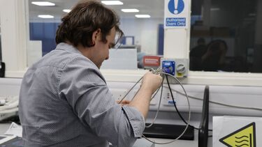 Photograph of Dr. Matthew Hobbs working in the lab at the University of Sheffield, pictured with the infrared thermometer contained within its box