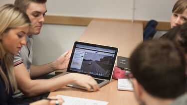Four students working around a laptop