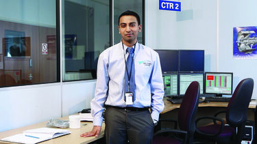 An English graduate wearing a suit, stood in an office.