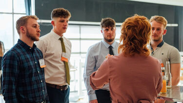An alumni speaking to four students