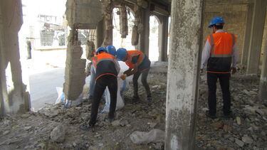 A group of academics inspecting rubble inside a damaged building in Syria
