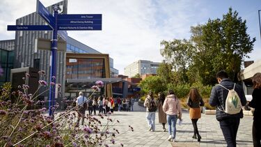 Students on the University concourse next to a signpost