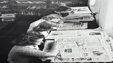 A line of women with 1950s hairstyles and clothing reading newspapers in a library.