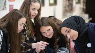A group of young students work together on an outreach activity. 