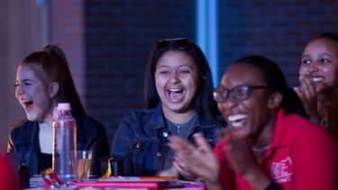A group of young students laughing together with a University of Sheffield student ambassador. 