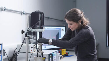 Woman with brown hair working in a laboratory using a microscope