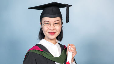 Bonny wears a graduation cap and gown, holding a diploma