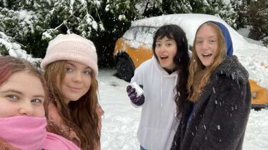 Four students posing in the snow with scarves and hats