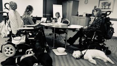 Three disabled researchers and two assistance dogs sat at an office table