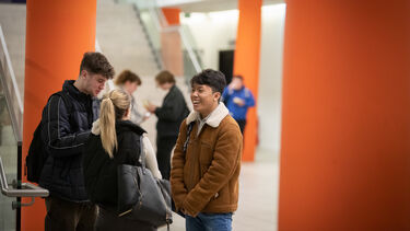 A group of three young people speaking and laughing together.