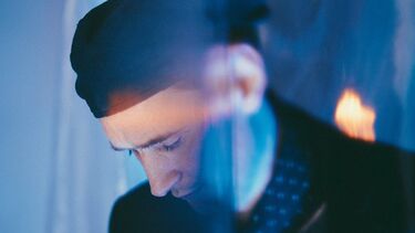 A photograph of composer Erland Cooper looking downwards, taken by photographer Alex Kozobolis