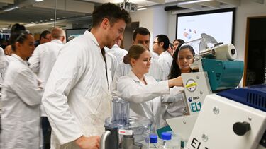 People in lab coats interacting with a piece of machinery