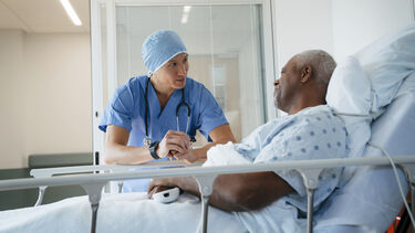 Photo of a surgeon talking to a patient in a hospital bed