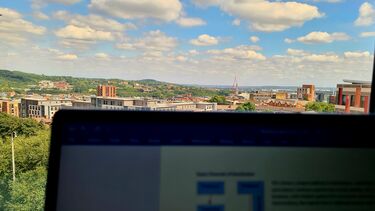 A laptop with the Sheffield skyline out of the window.