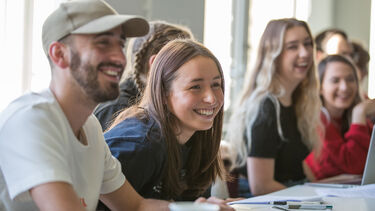 A photo of students smiling and chatting during a seminar