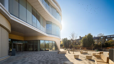 A view of the Faculty of Social Sciences building, the Wave, from the outside. A tall building with large glass windows.