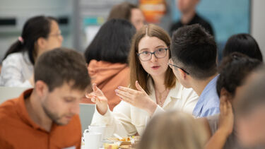 People at an event sitting at tables talking with food and cups