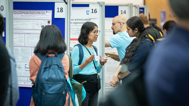 People standing talking in front of a poster display