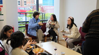 Attendees of the lecture outside the moot court sharing something to eat and drink whilst talking about the lecture they have just seen. 
