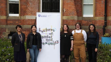 5 people including Surabhi and and the speaker outside the front of Bartolome house with the banner between them 2 on the left side 3 on the right side 