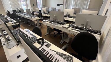 room shot of apple mac mini computers and music keyboards