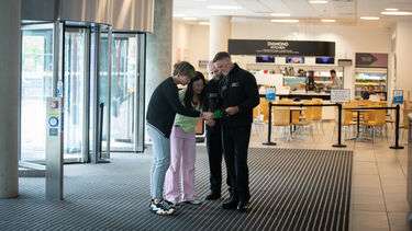 Two students and a security officer stood inside the door of The Diamond building, with the cafe in the background