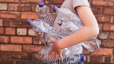 person carrying empty plastic water bottles