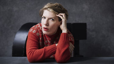 artist Paulien Cornelisse in a red jumper looks at the camera while supporting her hear on the side