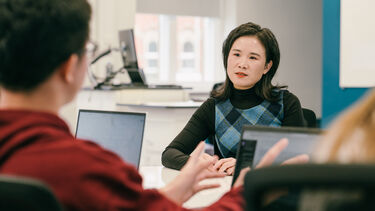 Image of Dr Bo Wang talking to a student from across a table