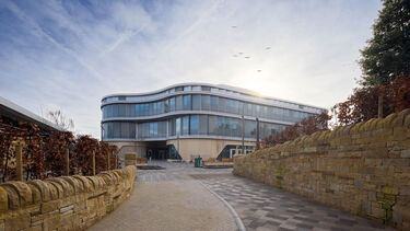 The wave, a large, curved glass building, standing tall in the sunshine. 