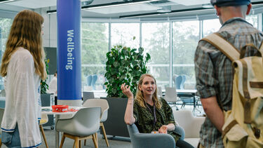 A staff member sat down talking to two students