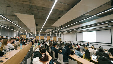 a large modern lecture theatre full of hundreds of people. 