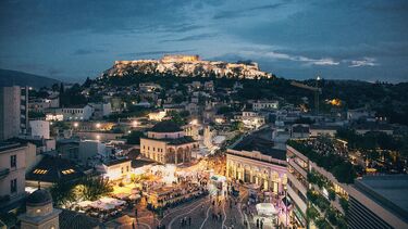 A bustling european city at dusk, with lots of buildings and lights.