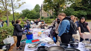 Groups of people looking at tables full of kitchen and homeware items