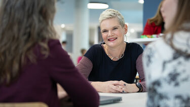 Dr Anna Weighall at a table in conversation with colleagues.