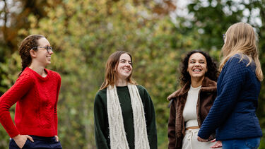 Four girls stood together laughing