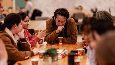 Students sat around a table with coffee cups