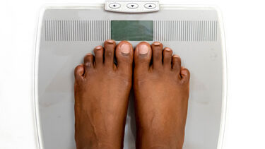 A pair of feet standing closely together on weighing scales