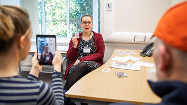 Woman holding flashcards is recorded on a tablet