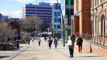 People walking down the street of red brick and modern buildings