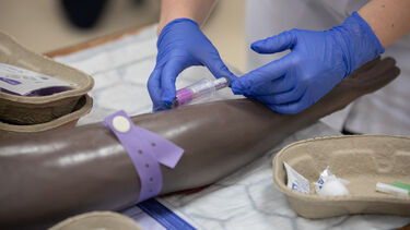 Nursing student practices blood drawing skills on a mannikin
