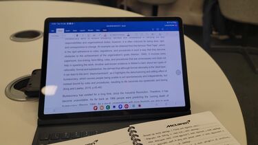 A laptop and notebook on a desk.