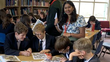 student looking at the camera with papers in her hadn clearly working with young people in a school setting