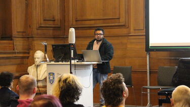 Dr Gee Semmalar presenting from behind a lectern