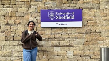 Kanak Soni stood beside a sign for The Wave building