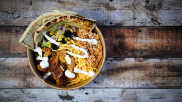 Bowl with rice, chicken, salad, cheese and some flatbreads in it