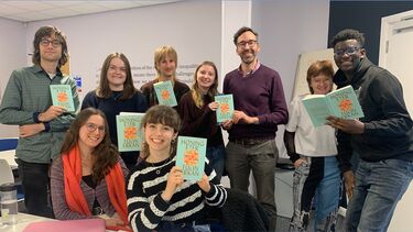 group of 9 students each holding up a book and smiling to the camera. the book says Honingeters